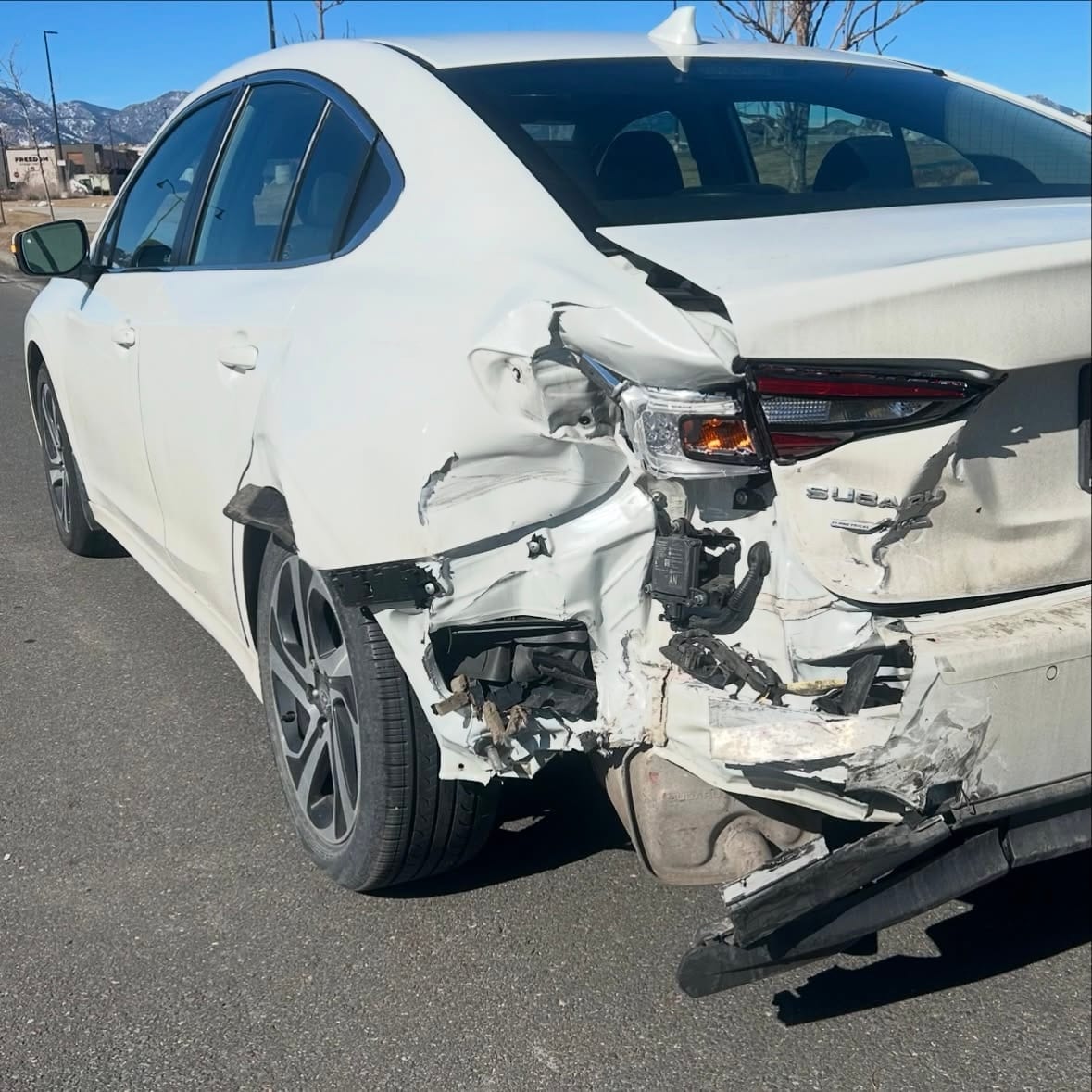 White Subaru with heavy rear-end collision damage, before repair