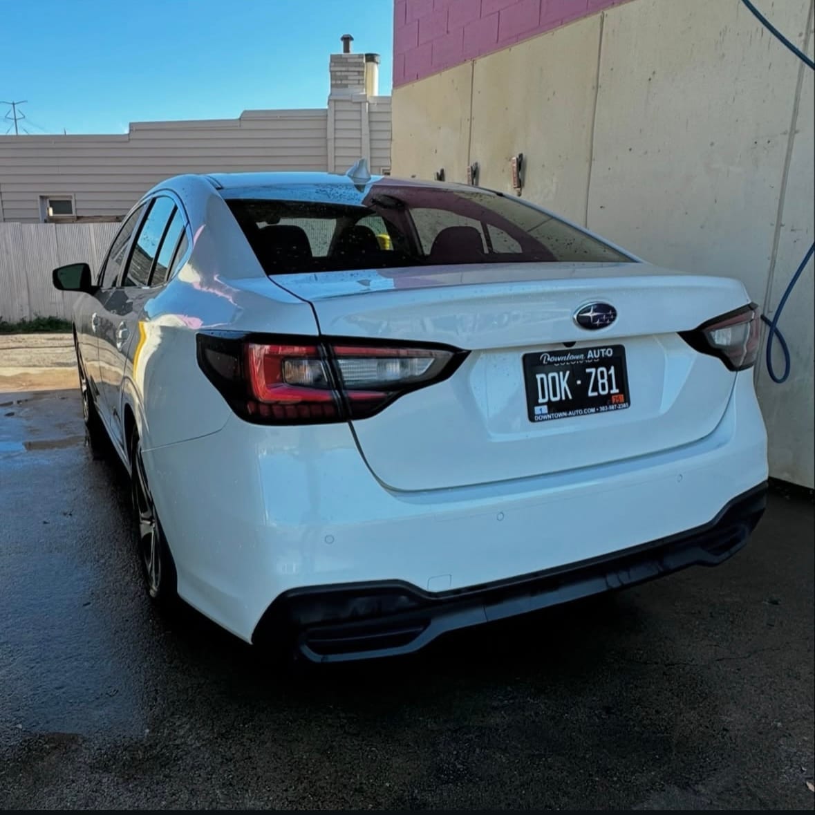 Rear of a white Subaru after collision repair, bumper and taillights restored